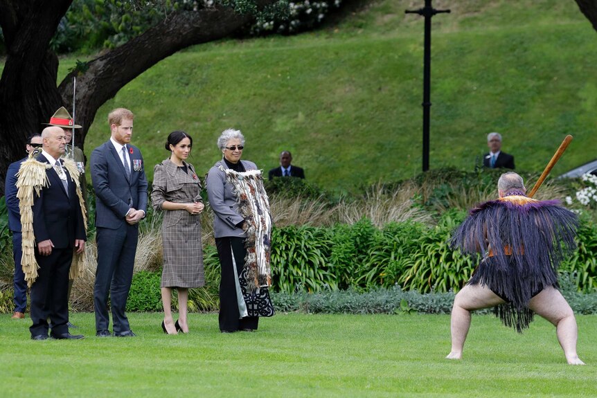 Meghan and Prince Harry stand as a Maori warrior makes an official welcome