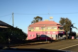Viewed from a car, a large pink building looms up on an otherwise quiet highway