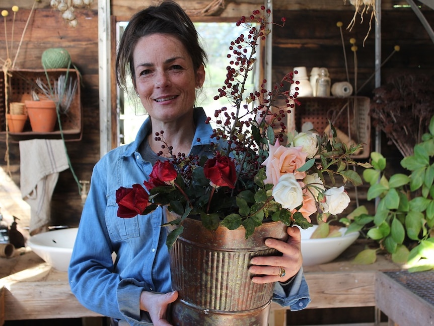 Organic flower grower Danielle White holding up a bouquet of flowers at her property.