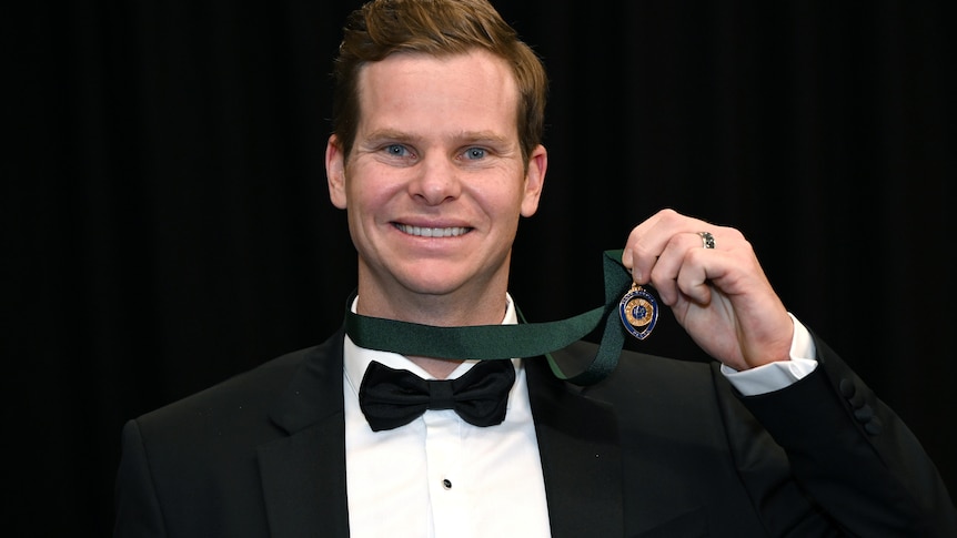 Steve Smith, dressed in a tuxedo, smiles and displays his Allan Border medal.