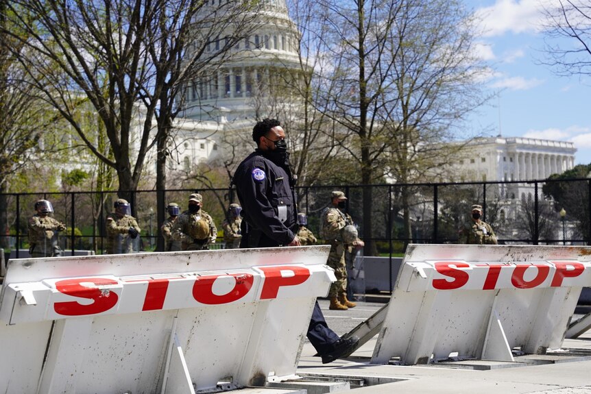 A police officer walks through two barricades painted with the word STOP in large red letters.