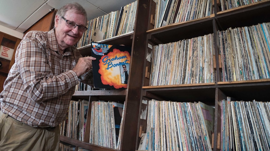 Ian Damon pulls record from shelf.