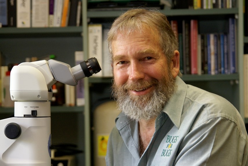 Dan Papacek poses next to a microscope.