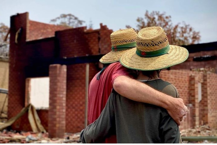 A couple look over their burnt out home following the bushfires. 