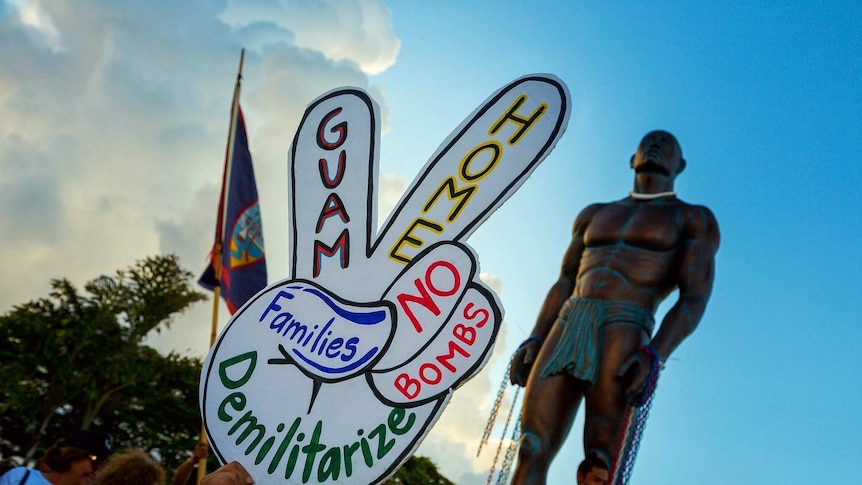 Guam protester holds sign demanding peace in public rally in response to North Korean crisis.