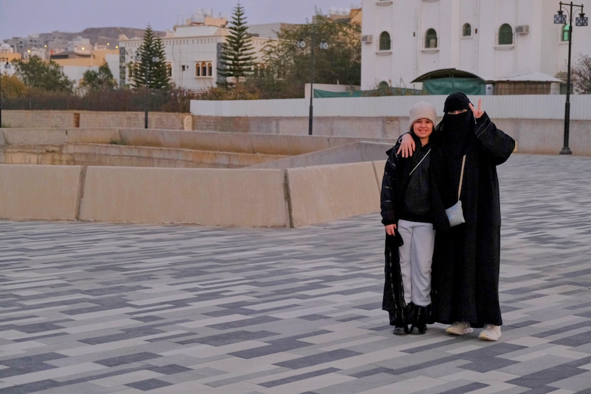 A mother and daughter pose for a photo in the street.