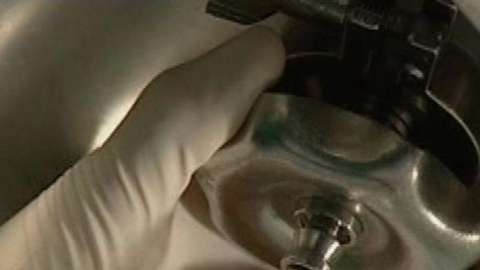 Gloved hand manipulates blood product in vial