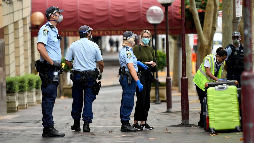 Police officer in masks usher travellers and their bags into the InterContinental Hotel