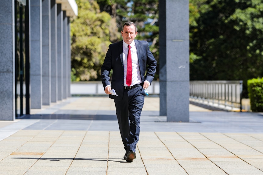 A wide shot of Mark McGowan walking outside Dumas House.