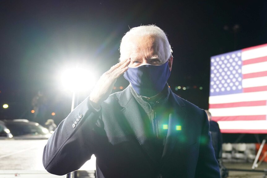 Joe Biden in a face mask saluting