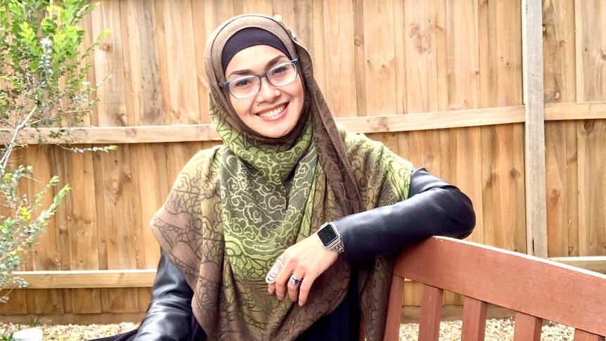 A woman sitting on a bench in a backyard