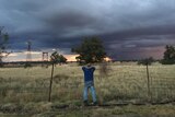 A farmer watches storm clouds rolling in.