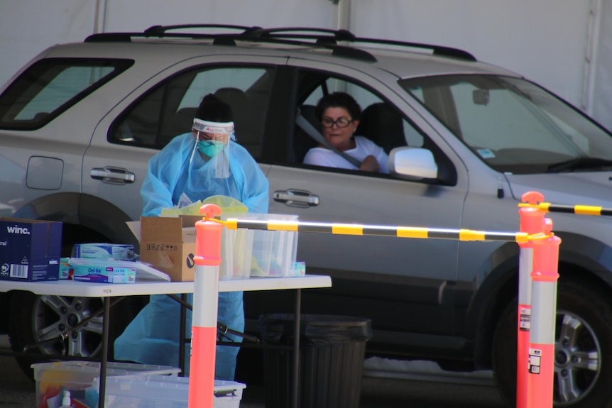 Medical worker prepares to test woman at drive through clinic in Perth.