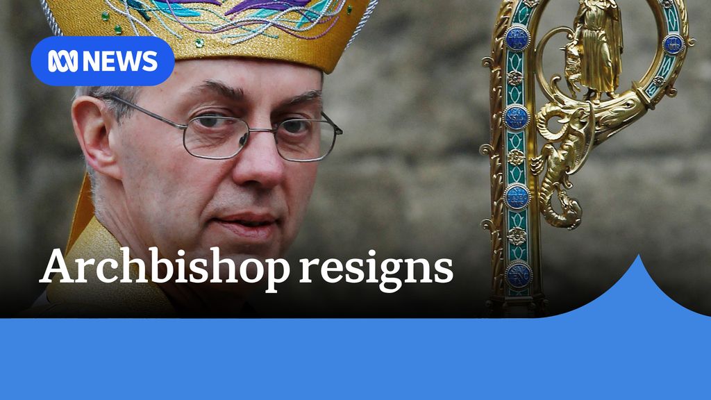 Archbishop resigns: A man with glasses wearing an ornate golden hate and a golden rod.