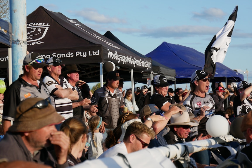 A crowd of people cheering in black and white. 