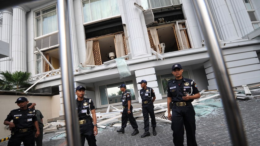 Company guards secure the damaged facade of the Ritz-Carlton hotel in Jakarta