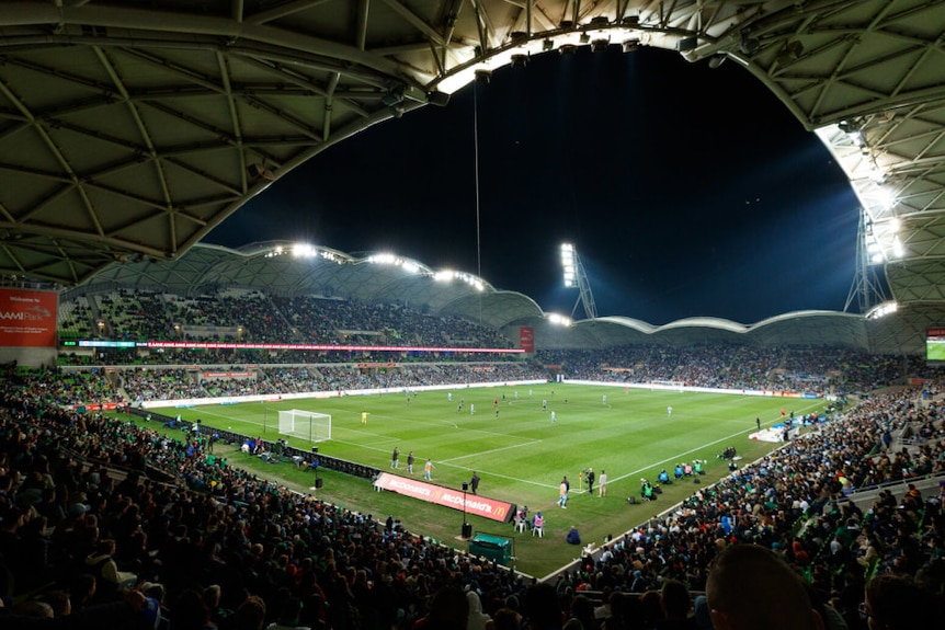 A soccer game is played at night with a capacity crowd