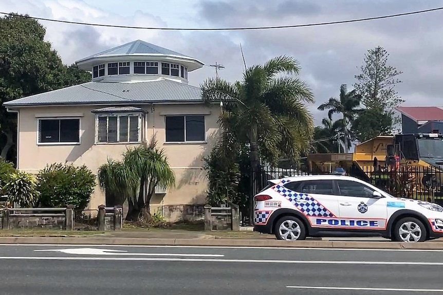 An older style house with a turret at the top and a police car driving past.