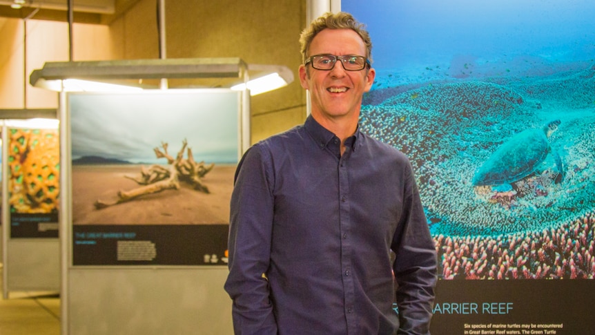 Photographer Gary Cranitch standing with his exhibition The Great Barrier Reef.