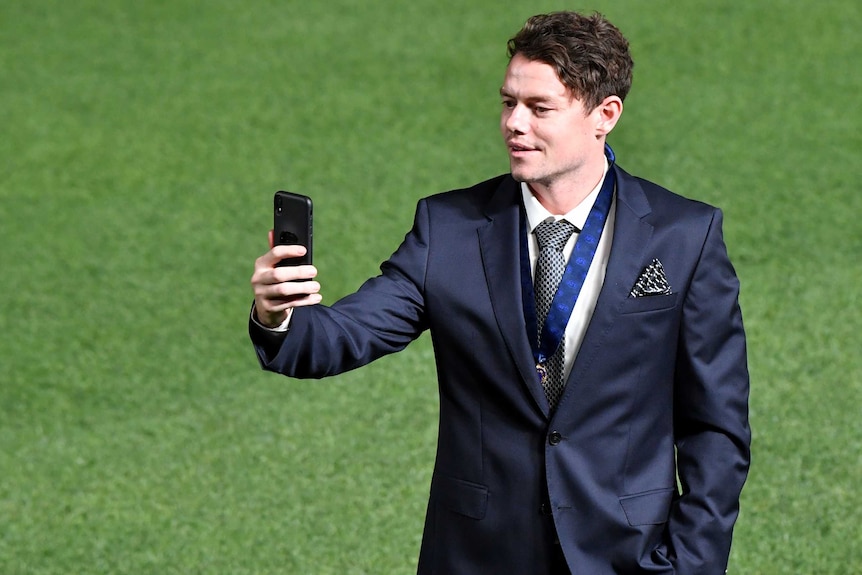 Standing on the Gabba grass, Lachie Neale takes a selfie while wearing his Brownlow Medal