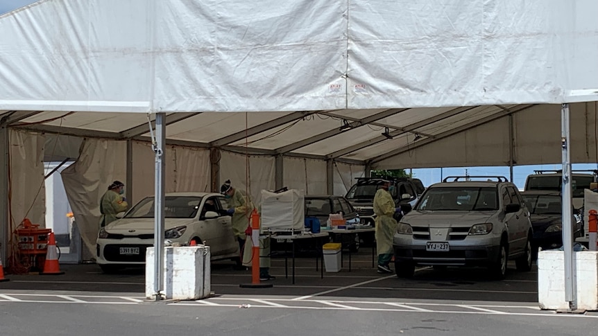 Cars under a tent where people are being tested for covid