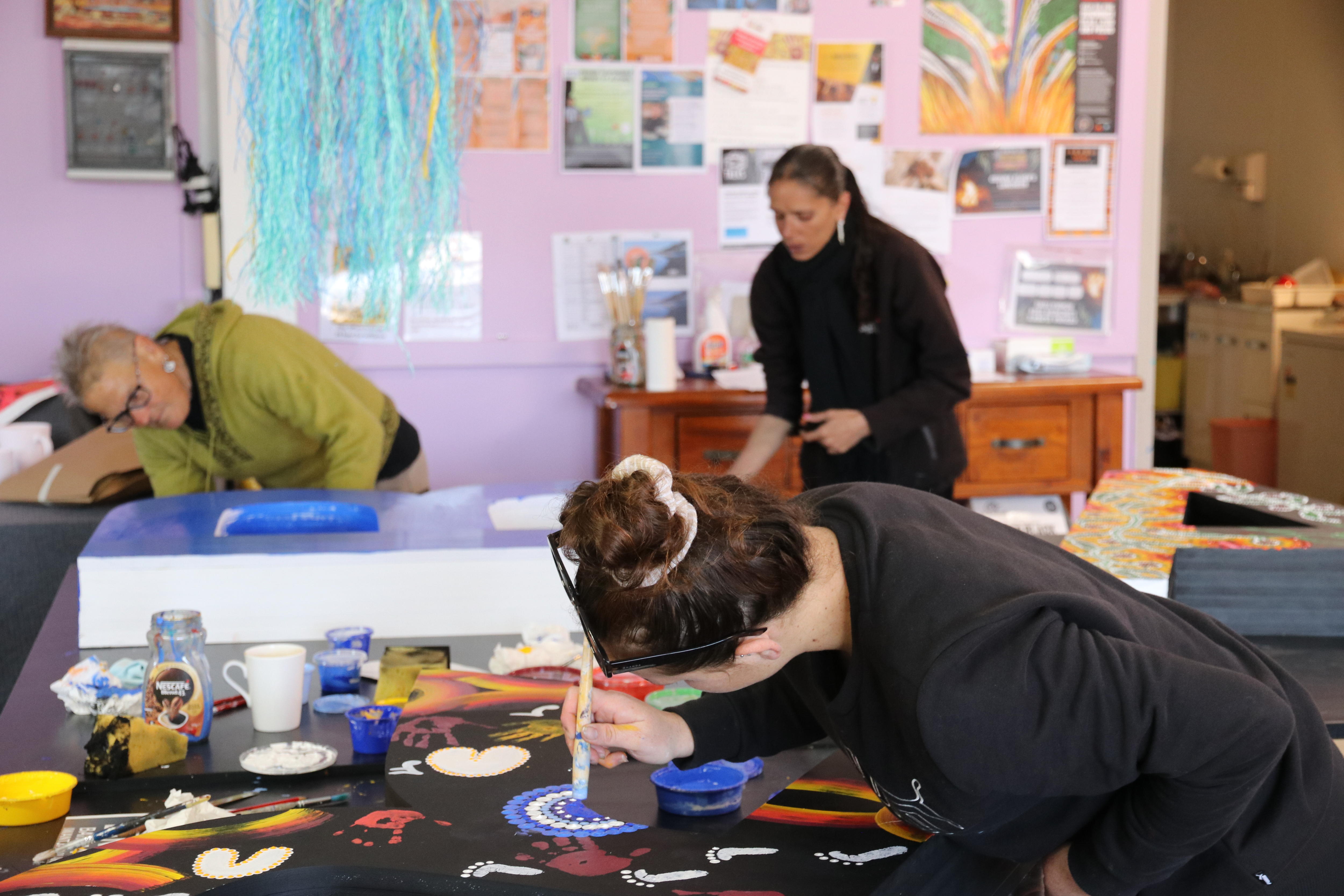 artists in a colourful room paint large letters 