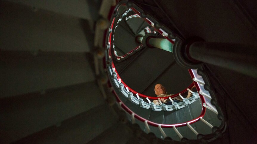 Caretaker Tony Symes peers down over the railing from inside the spiral staircase inside the lighthouse.