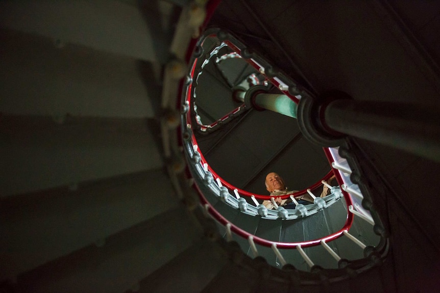 Caretaker Tony Symes peers down over the railing from inside the spiral staircase inside the lighthouse.