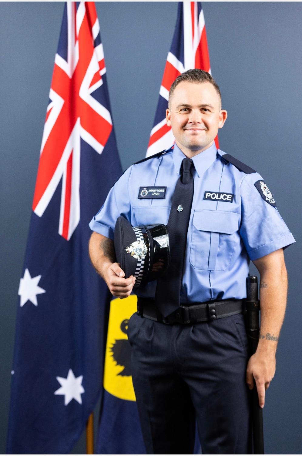 A police officer stands in front of two Australian flags.
