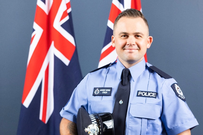 A police officer stands in front of two Australian flags.
