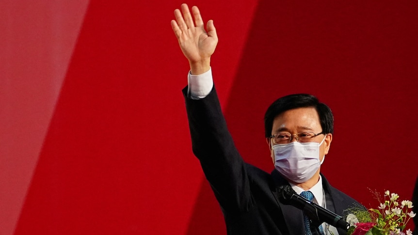 Masked man waves whilst holding floral bouquet. 