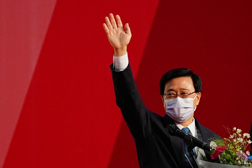 Masked man waves whilst holding floral bouquet. 