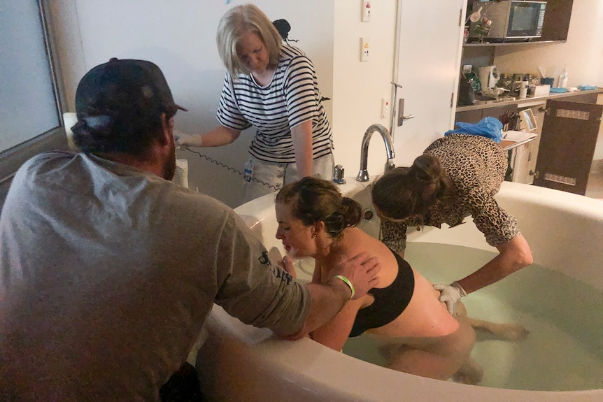 Toowoomba mother Andy Martin labours in bath tub supported by husband and cared for by two midwives.