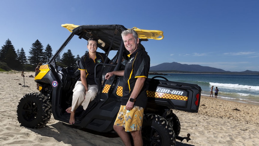 An ATV at the beach and two people smiling.