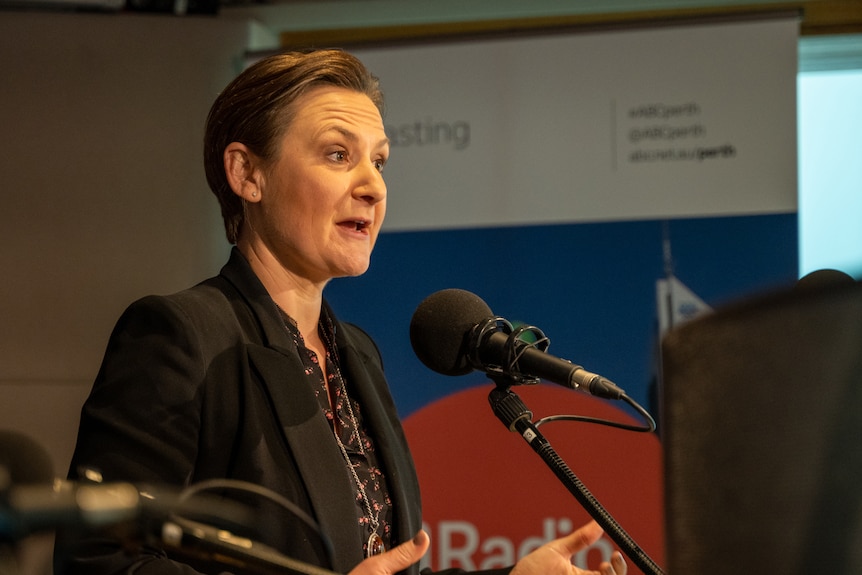 A close-up side-on shot of WA Health Minister Amber-Jade Sanderson speaking into a microphone in a radio studio.