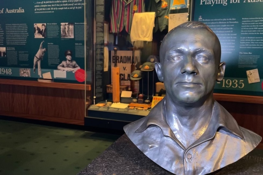A bust of Don Bradman on display in a museum.