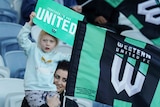 A woman and her daughter fly Western United flags in the crowd at an A-League Men match.