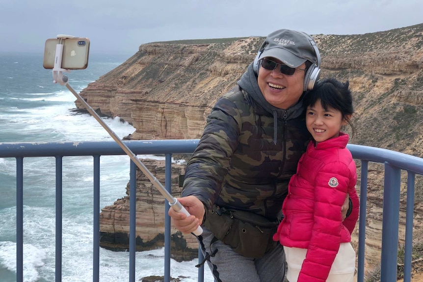 A father takes a selfie with his daughter.