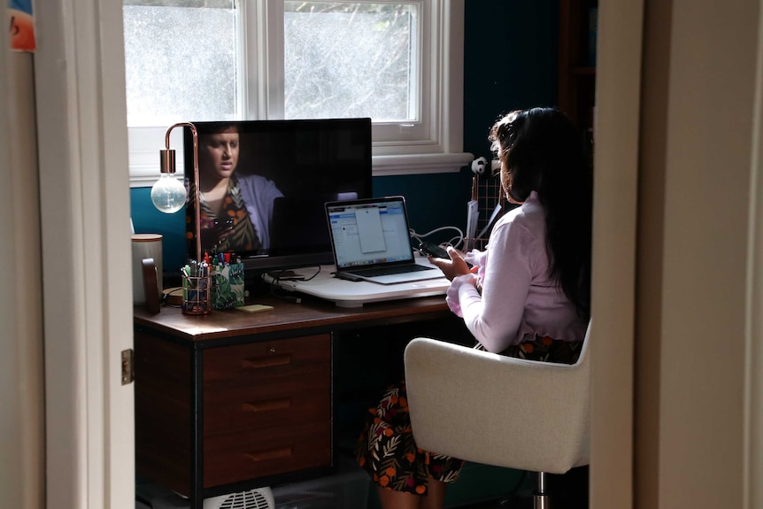 A woman at a home office looking at her phone