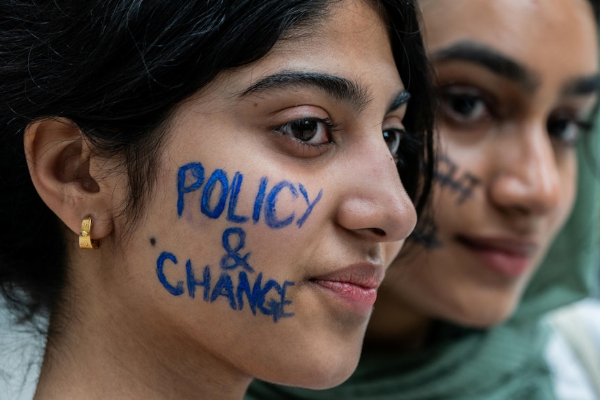 A young protester has 'POLICY & CHANGE' written on her face. 