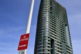 A sign that says 'no stopping' in the foreground in front of a tall apartment building, Opal Tower.