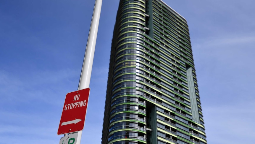 no stopping sign with an apartment building in the backgournd