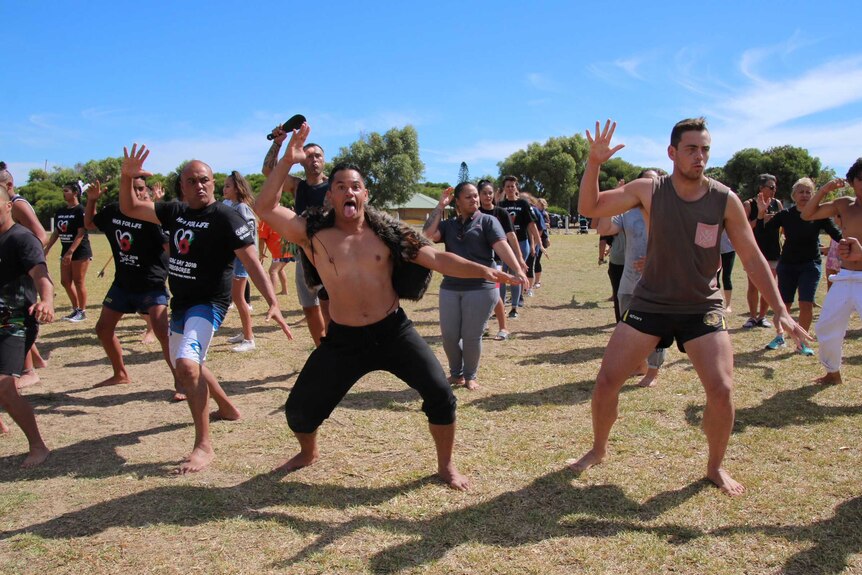 A group of people perform the haka in a park.