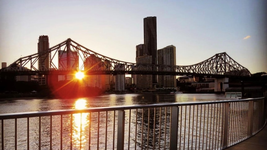 The sun sets behind Brisbane's Story Bridge and Brisbane River in the CBD.