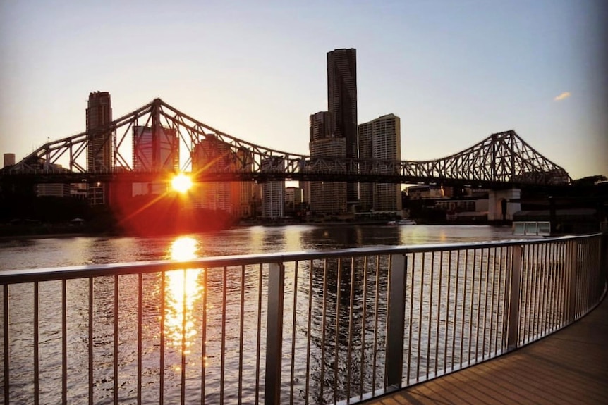 The sun sets behind Brisbane's Story Bridge and Brisbane River in the CBD.