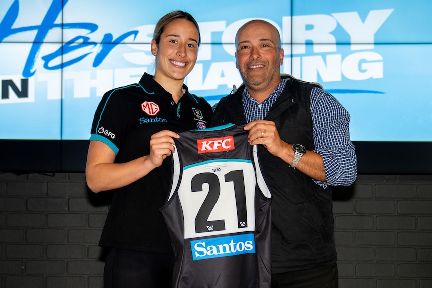 Amelie Borg is presented her Port Adelaide jumper, holding it next to her father