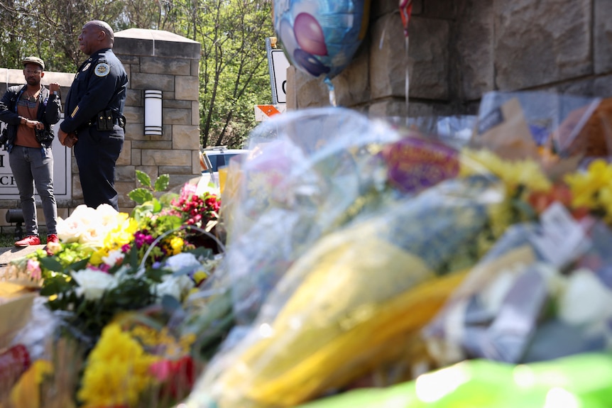 Nashville Chief of Police John Drake stands next to a memorial covered in flowers at the school entrance.