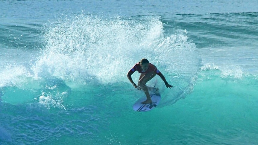 A woman on her surf board rides a wave.