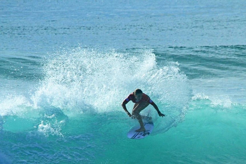 A woman on her surf board rides a wave.