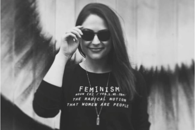 Nicola Thorp wears a shirt with the word "Feminism" on it.